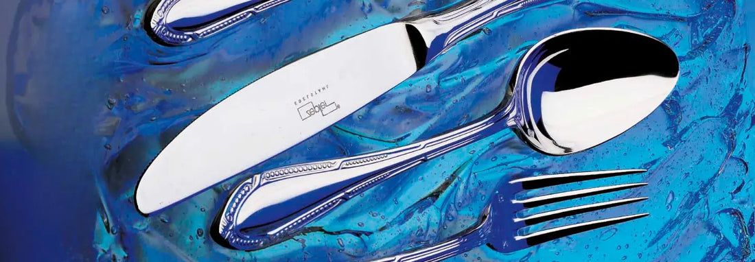 Premium mirror-polished stainless steel cutlery arranged around an elegant dining table set for six, showcasing the style of Zepter 36-piece cutlery sets.